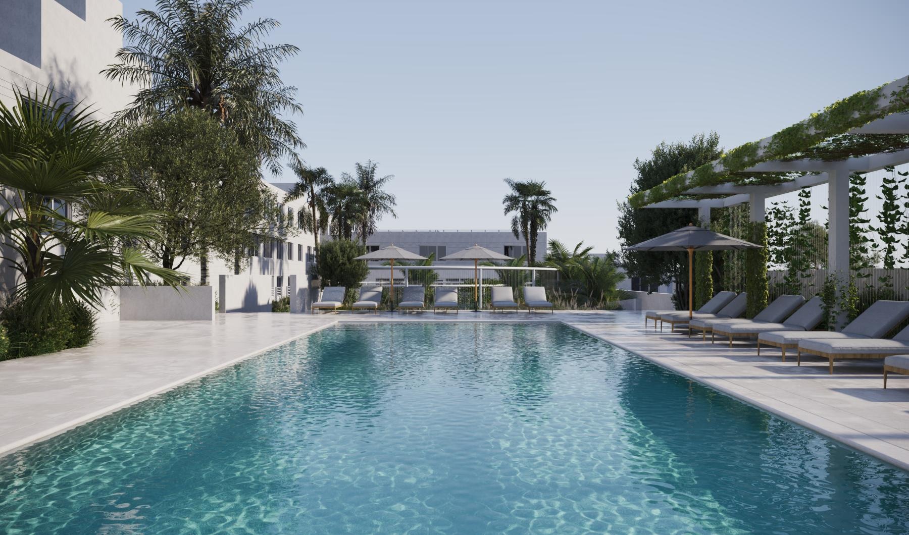 a pool with lounge chairs and umbrellas by a building